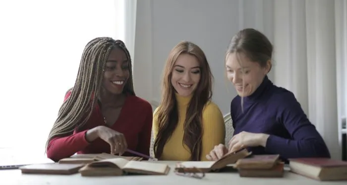 woman of different skin tones and races reading books together at a table